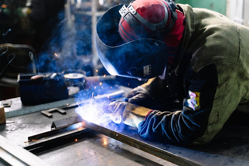 A welder welding in protective clothing and helmet
